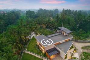 A modern two-story building with a prominent 'H' logo, surrounded by lush greenery and palm trees. - Jungle 9BR Ubud Paradise with spa! (Ubud)