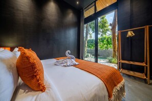 A modern hotel room with a large bed, a view of greenery outside, and a wooden shelf with hangers. - Jungle 9BR Ubud Paradise with spa! (Ubud)