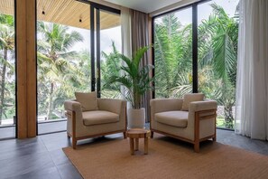 A modern living room with two beige armchairs, a small wooden table, and a large potted plant. - Jungle 9BR Ubud Paradise with spa! (Ubud)