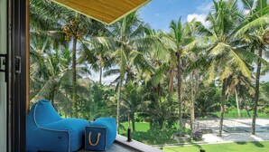 Ein Zimmer mit großem Fenster und Blick auf einen tropischen Garten mit Palmen.