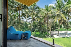 Ein Zimmer mit großem Fenster und Blick auf einen tropischen Garten mit Palmen.
