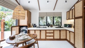 Una cocina moderna con comedor, que incluye una isla central, armarios empotrados y una lámpara colgante.