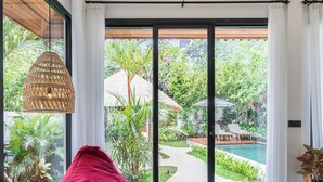 Un interior moderno con un gran ventanal corredero que da a una piscina y jardín.