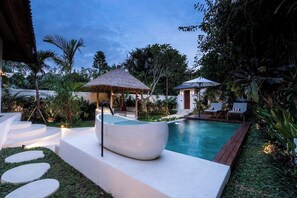 A swimming pool with a modern design, surrounded by a garden with steps leading to a covered area. - Luxe 2BR Villa in Ubud w Garden Bath, Patio & Pool (Gianyar Regency)