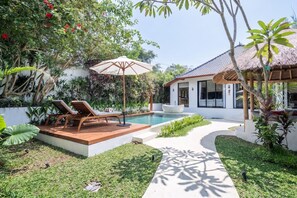 A modern outdoor pool area with lounge chairs, a thatched-roof structure, and lush greenery. - Luxe 2BR Villa in Ubud w Garden Bath, Patio & Pool (Gianyar Regency)