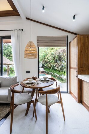 A modern dining area with a round table, wooden chairs, and a woven pendant light. - Luxe 2BR Villa in Ubud w Garden Bath, Patio & Pool (Gianyar Regency)