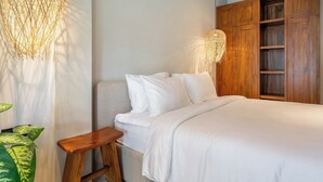 A bedroom with a bed, bedside tables, a wooden wardrobe, and hanging lamps. - Cozy 3BR Villa in Lush Ubud w Pool, Patio & Garden (Gianyar Regency)