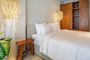 Ein Schlafzimmer mit einem Bett, Nachttischen, einem Holzschrank und Pendelleuchten.
