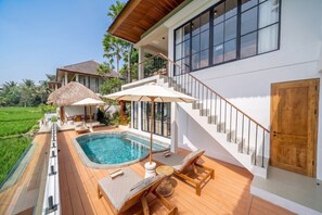 A modern house with a swimming pool, outdoor seating, and a staircase leading to a balcony. - Cozy 3BR Villa in Lush Ubud w Pool, Patio & Garden (Gianyar Regency)