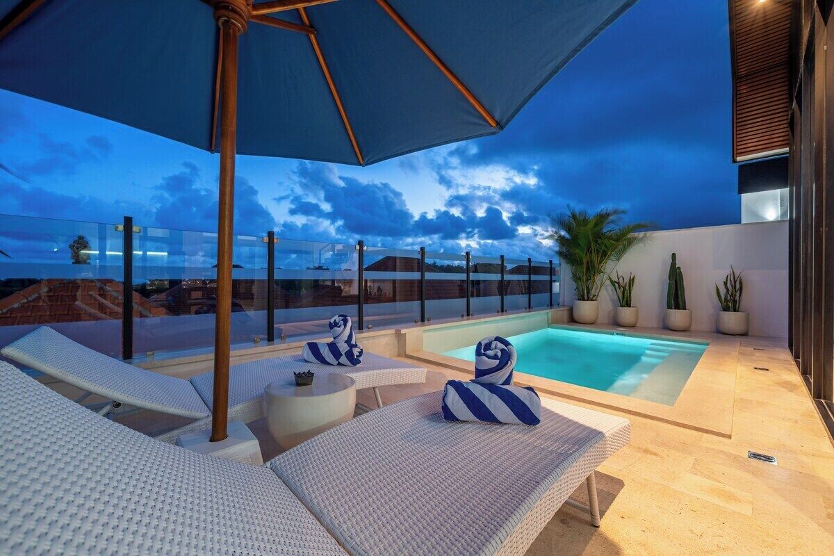 Un espace piscine sur le toit, avec des chaises longues et un jacuzzi.