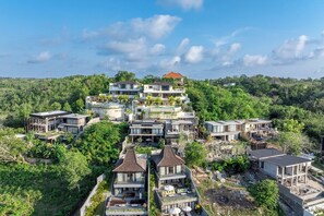 A residential area with multiple houses on a hillside, surrounded by greenery. - Luxe 4BR Villa w Rooftop, Cinema, Ocean View (Badung Regency)