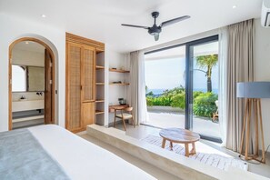 Ein modernes Schlafzimmer mit einem Bett, einem Schreibtisch und Blick ins Freie.