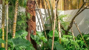 A lush garden with various tropical plants and a bamboo fence. - Badung's 2BR Gem w Private Pool & Beach Nearby (Badung Regency)