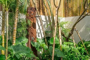 A lush garden with various tropical plants and a bamboo fence. - Badung's 2BR Gem w Private Pool & Beach Nearby (Badung Regency)