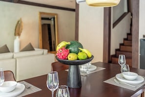 A dining table with a fruit centerpiece, white plates, and clear glasses. - Badung's 2BR Gem w Private Pool & Beach Nearby (Badung Regency)