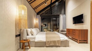 A modern bedroom with a large bed, a TV mounted on the wall, and a wooden cabinet. - Badung's 2BR Gem w Private Pool & Beach Nearby (Badung Regency)