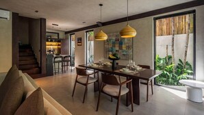 A modern dining area with a wooden table, chairs, and pendant lighting. - Badung's 2BR Gem w Private Pool & Beach Nearby (Badung Regency)