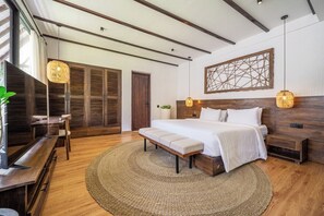 A modern bedroom with a large bed, wooden flooring, a TV, and a decorative wall piece. - Tropical 3BR Villa in Ubud w Pool, Patio & Garden (Ubud)