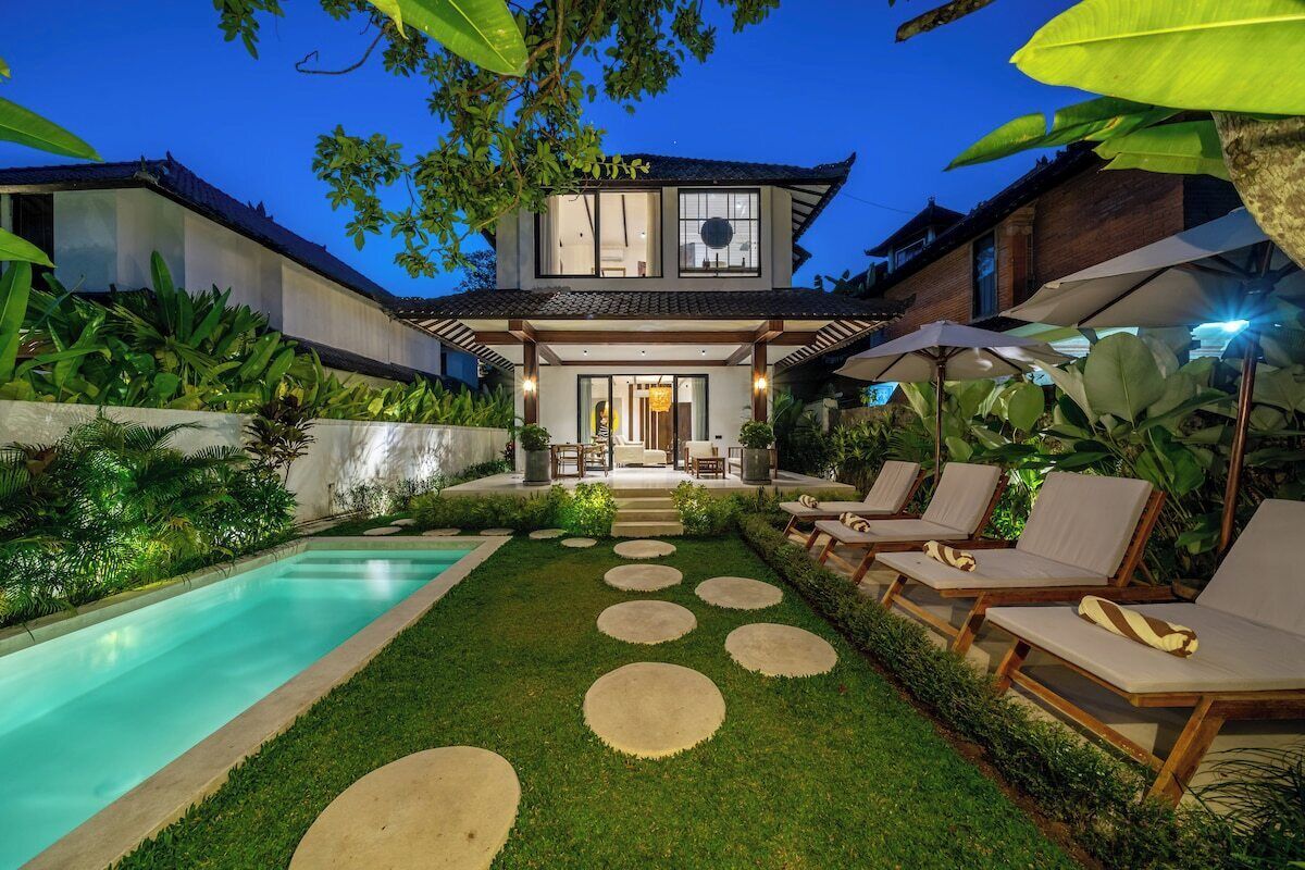 A modern house with a swimming pool, lounge chairs, and a well-maintained garden.