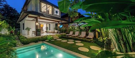 A modern house with a swimming pool, surrounded by lush greenery and a well-maintained garden.