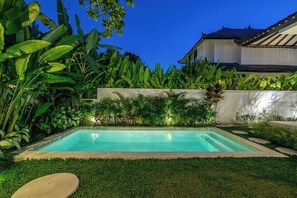 A rectangular swimming pool with a concrete edge, surrounded by lush greenery and a white wall. - Tropical 3BR Villa in Ubud w Pool, Patio & Garden (Ubud)
