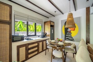 Une cuisine moderne avec un coin repas, comprenant une grande fenêtre, un four à micro-ondes et une table à manger pour quatre personnes.