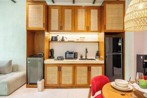Eine kleine Küche mit Holzausstattung, einer Mikrowelle, einem Kühlschrank und einem Essbereich mit Tisch und Stühlen.
