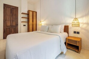 Ein Schlafzimmer mit einem großen Bett, einem Holzkopfteil, Nachttischen und Wandlampen.