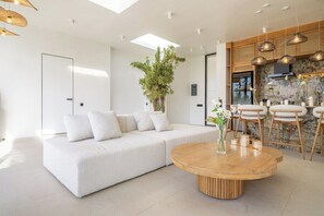 Un salon moderne avec un canapé, une table basse ronde en bois et un coin repas avec des chaises.