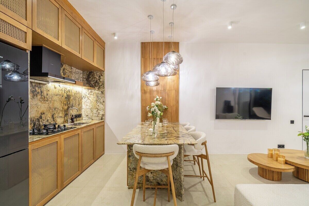 A modern kitchen with a marble countertop, wooden cabinets, and a built-in stove.