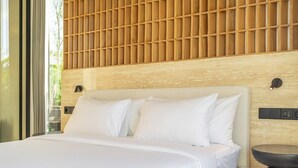 Moderni hotellihuone, jossa on suuri sänky, puinen pääty ja pieni pyöreä pöytä.