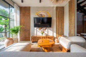 A modern living room with a flat-screen TV, a wooden coffee table, and a sofa. - Tropical 2BR in Ubud's Ricefields w Pool & Garden (Tegallalang)