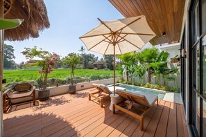 Eine Holzterrasse mit Liegestühlen und einem Pool mit Blick auf eine grüne Landschaft.