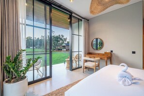 A modern hotel room with a large bed, a dining area, and a view of the outdoors. - Tropical 2BR in Ubud's Ricefields w Pool & Garden (Tegallalang)