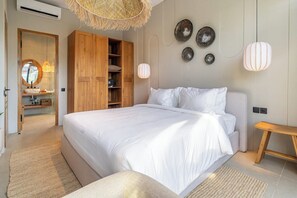 A bedroom with a large bed, wooden wardrobe, and a hanging light fixture. - Serene 2BR Retreat w Spacious Pool & Garden • Ubud (Gianyar Regency)