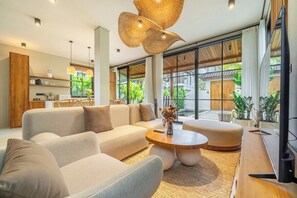 A modern living room with a sofa set, a coffee table, and a television. - Serene 2BR Retreat w Spacious Pool & Garden • Ubud (Gianyar Regency)