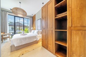 A bedroom with a large bed, wooden wardrobe, and a view of the outside. - Serene 2BR Retreat w Spacious Pool & Garden • Ubud (Gianyar Regency)