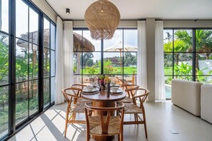 A dining area with a round table, six chairs, and a hanging light fixture. - Tranquil 2BR Villa in Ubud • Pool • Patio • Garden (Gianyar Regency)