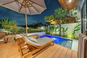 A wooden deck with lounge chairs and an umbrella, a swimming pool, and tropical plants. - Tranquil 2BR Villa in Ubud • Pool • Patio • Garden (Gianyar Regency)