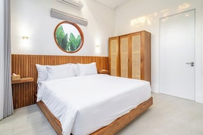 Une chambre à coucher avec une tête de lit en bois, un miroir rond, une armoire et une porte blanche.