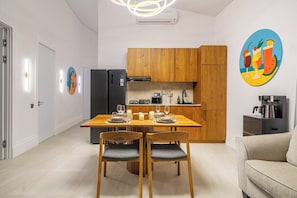 Une cuisine moderne avec des meubles en bois, une table à manger pour deux personnes et une machine à café.