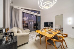 A modern living room with a sofa, dining table, and a TV. - New Jungle 3BR Villa+Beach Access+Huge Pool 10A (South Kuta)