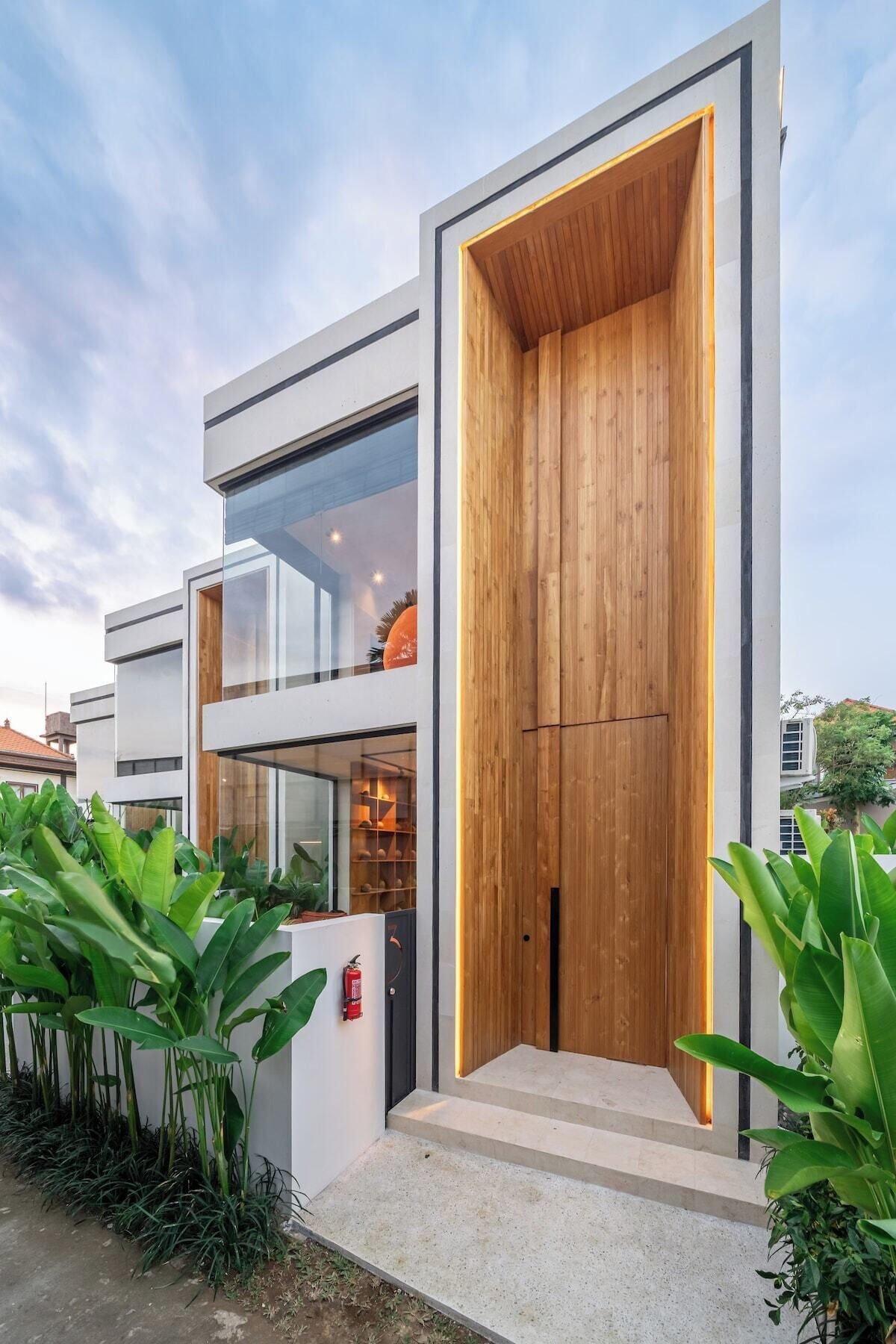 A modern two-story building with a large wooden door and glass windows.