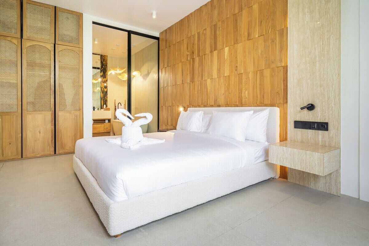 Ein modernes Schlafzimmer mit einem großen Bett, einem Holzkopfteil und einer eingebauten Ablagefläche.
