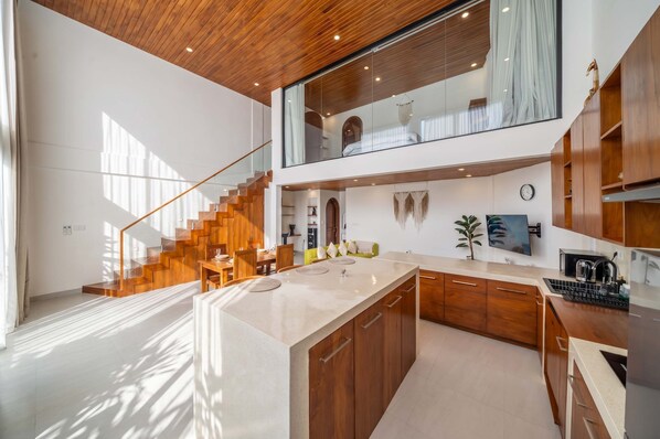 Een moderne keuken met een centraal eiland, houten kastjes, een trap en een eethoek.