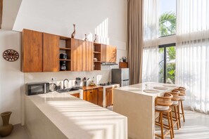 A modern kitchen with wooden cabinets, a central island, and bar stools.