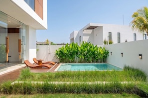A modern house with a swimming pool, wooden deck, and lounge chairs. - Modern 3BR villa - Ocean View & Rooftop, Pool (South Kuta)