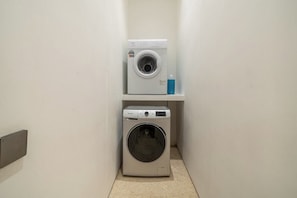 A laundry room with two washing machines and a shelf with a bottle. - Modern 3BR villa - Ocean View & Rooftop, Pool (South Kuta)