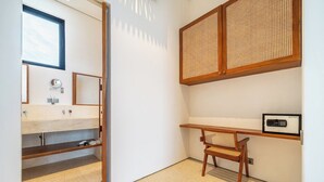 Un baño con tocador de madera, un espejo, un estante y una silla.