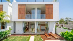 Una casa moderna de dos pisos con fachada de vidrio, listones de madera, piscina y césped cuidado.